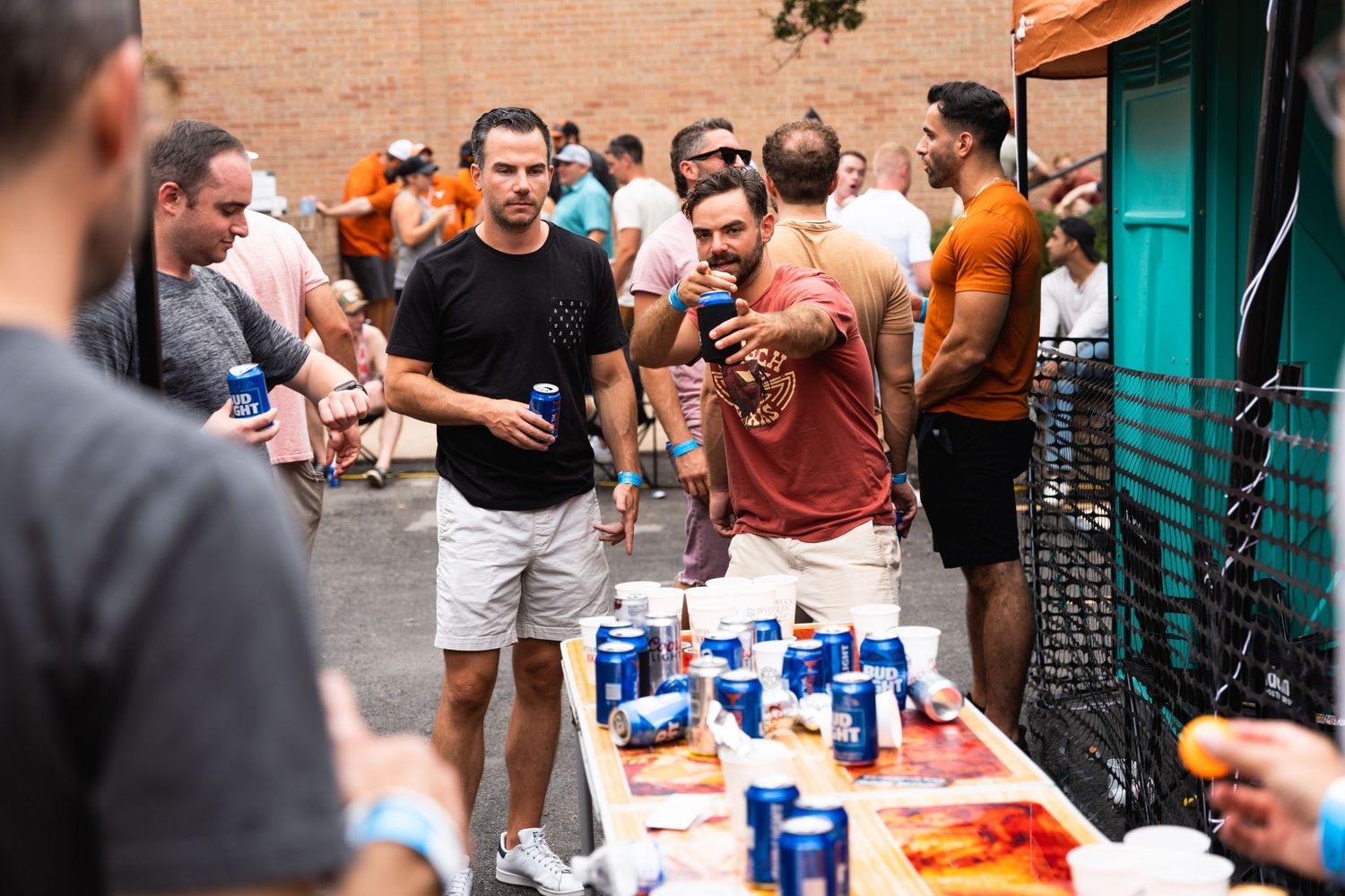 People socializing and playing games at outdoor party with blue cups and drinks.