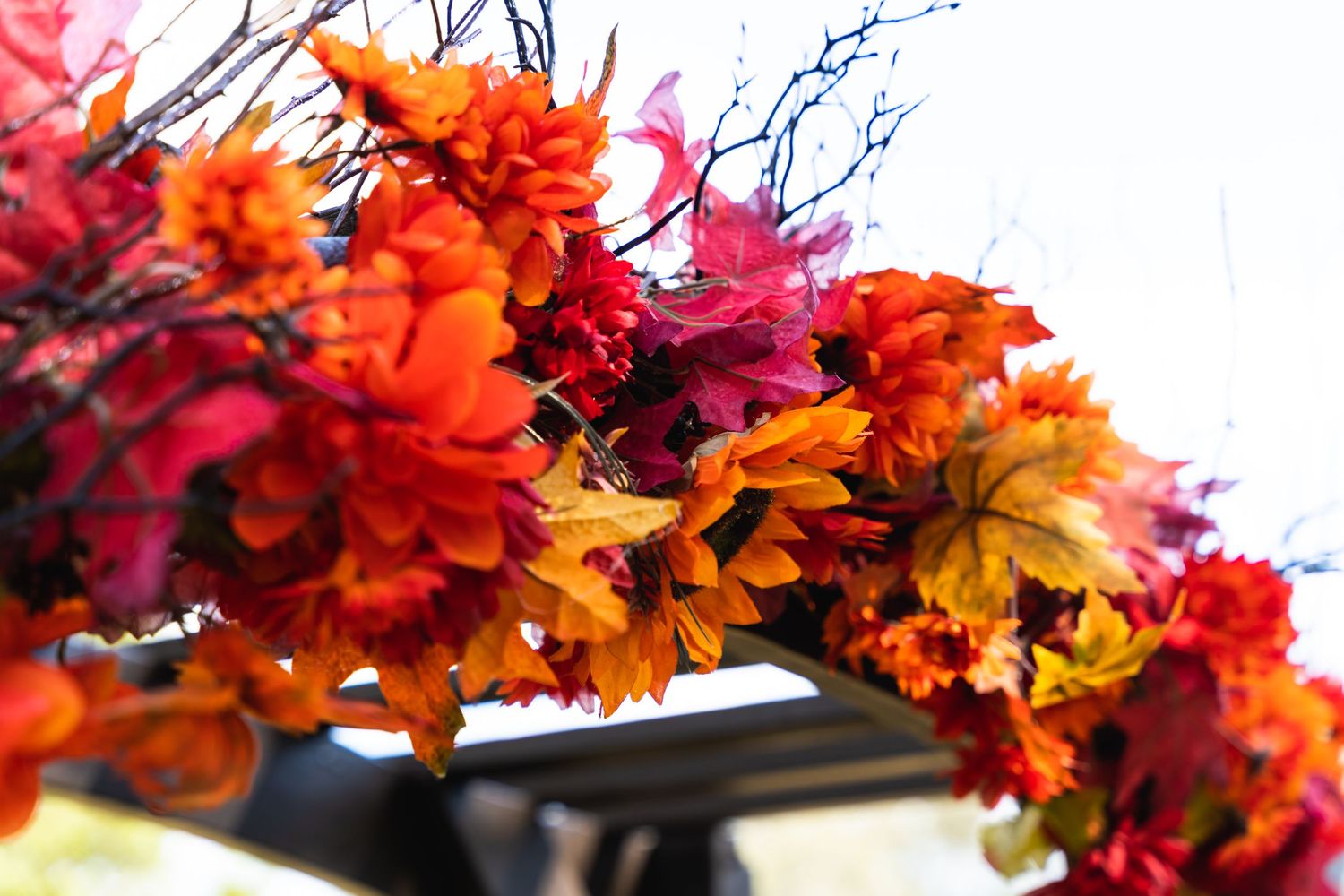 A vibrant fall floral arrangement with orange and red blooms against white background.