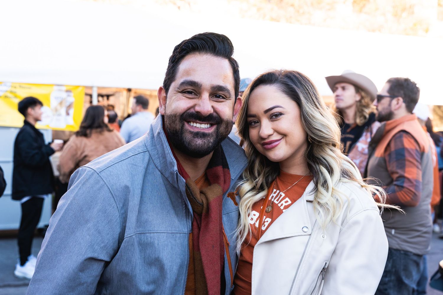 Couple smiling together at an outdoor social gathering.