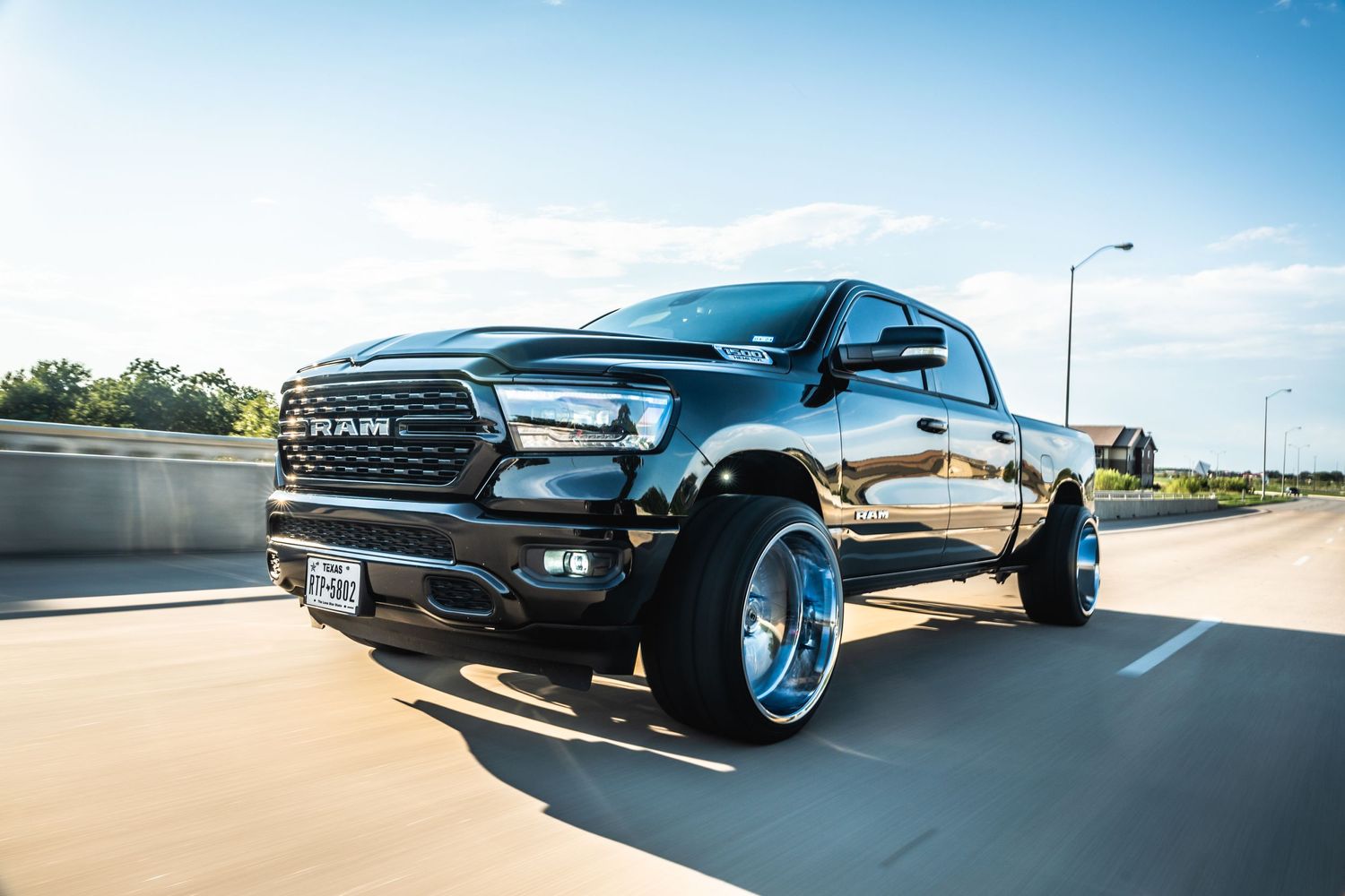 Modified RAM 1500 truck showcasing custom suspension and chrome wheels during motion shot.