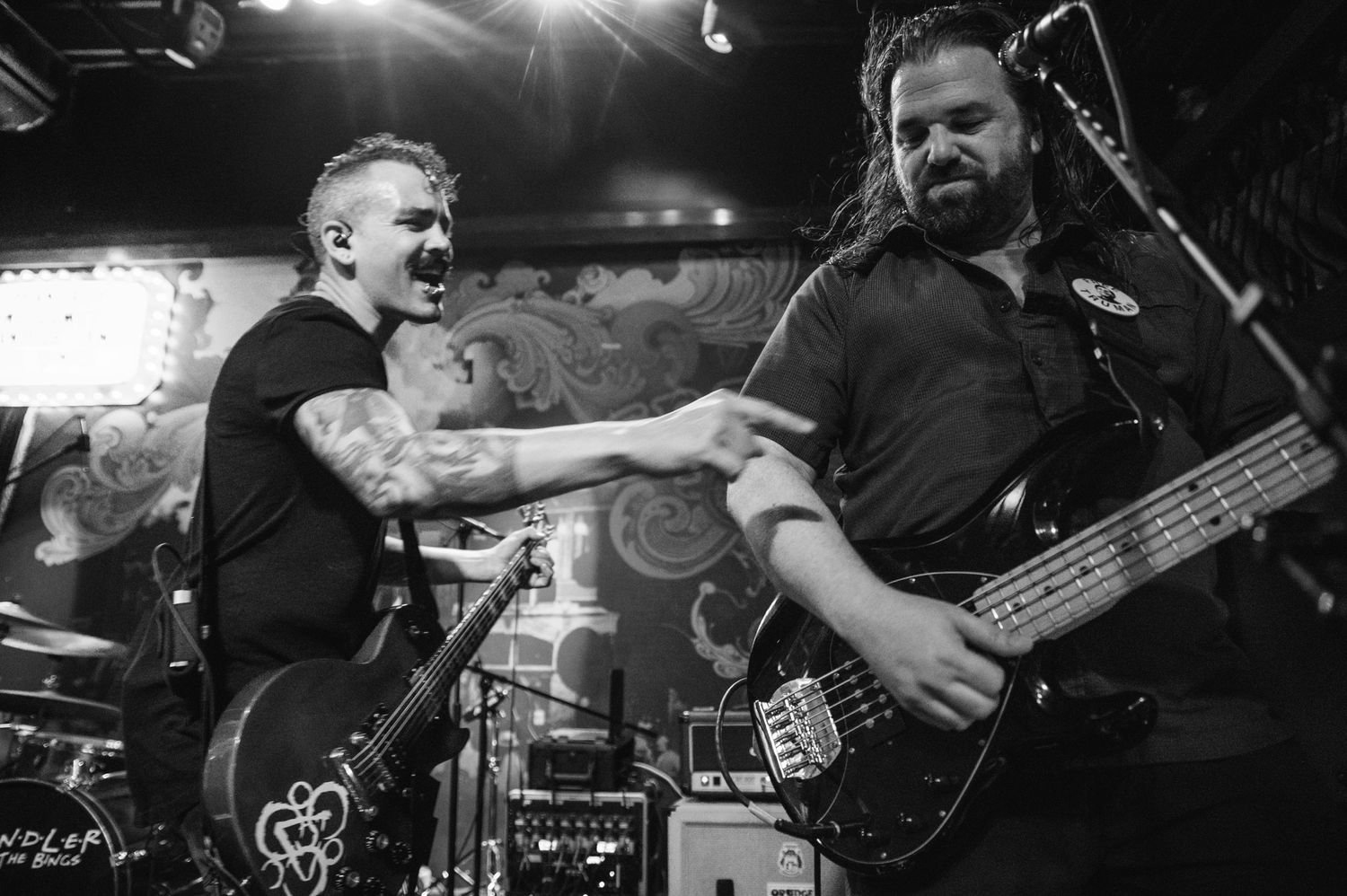 Black and white photo of performers energetically playing instruments on stage.