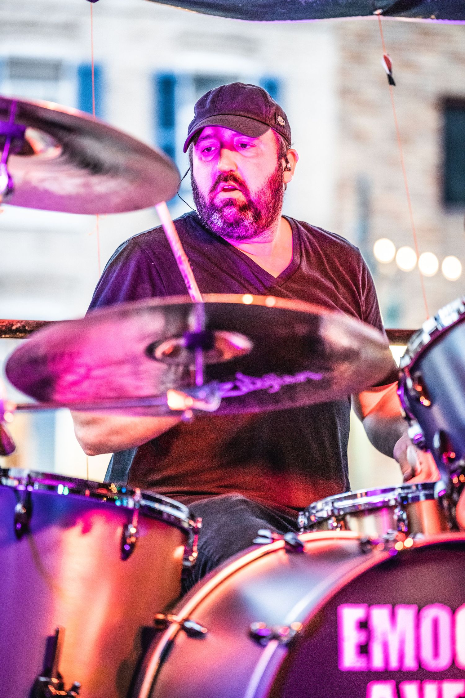 Drummer performing on stage with purple lighting and drum kit.