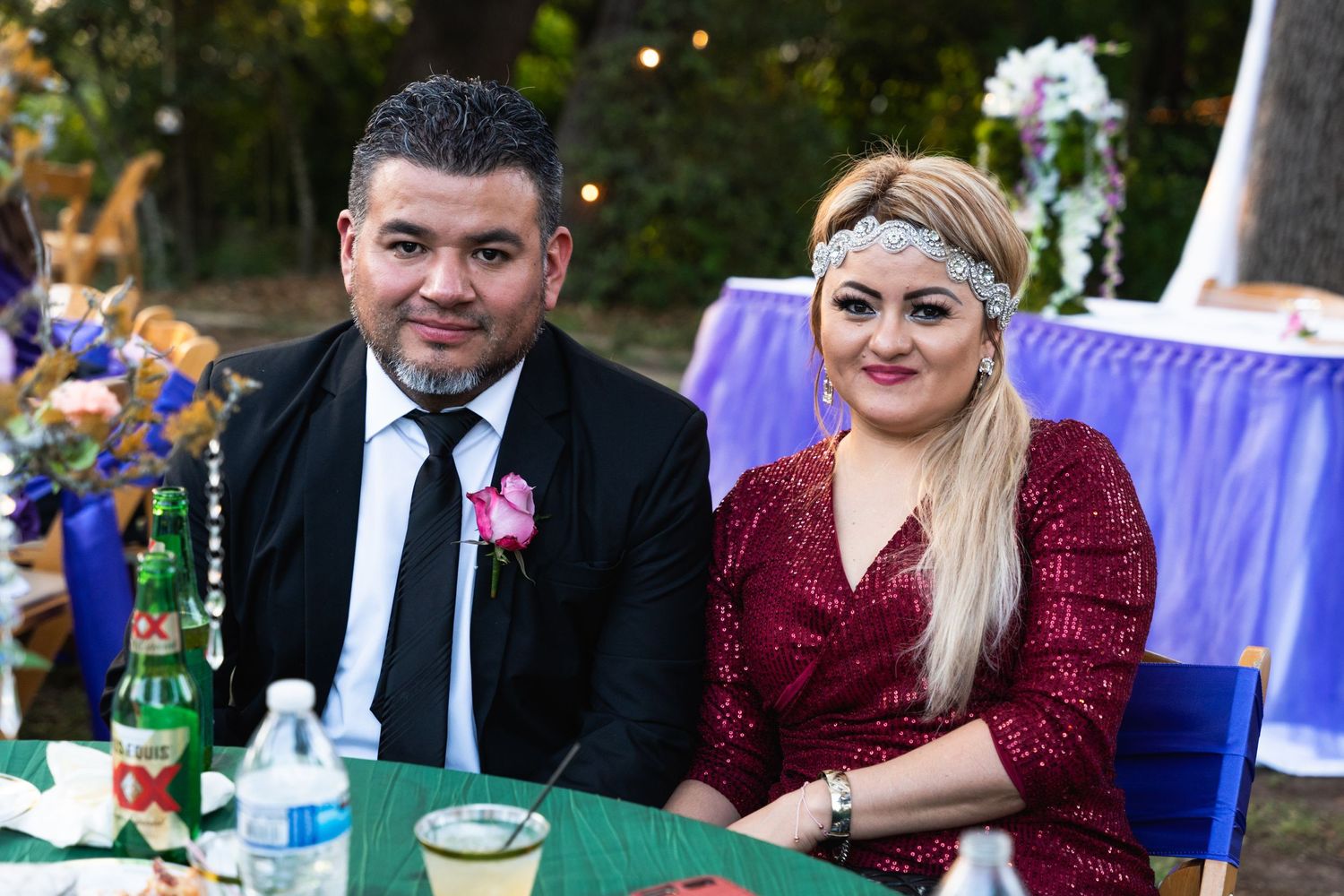 Wedding guests seated at a decorated outdoor table with purple decor.