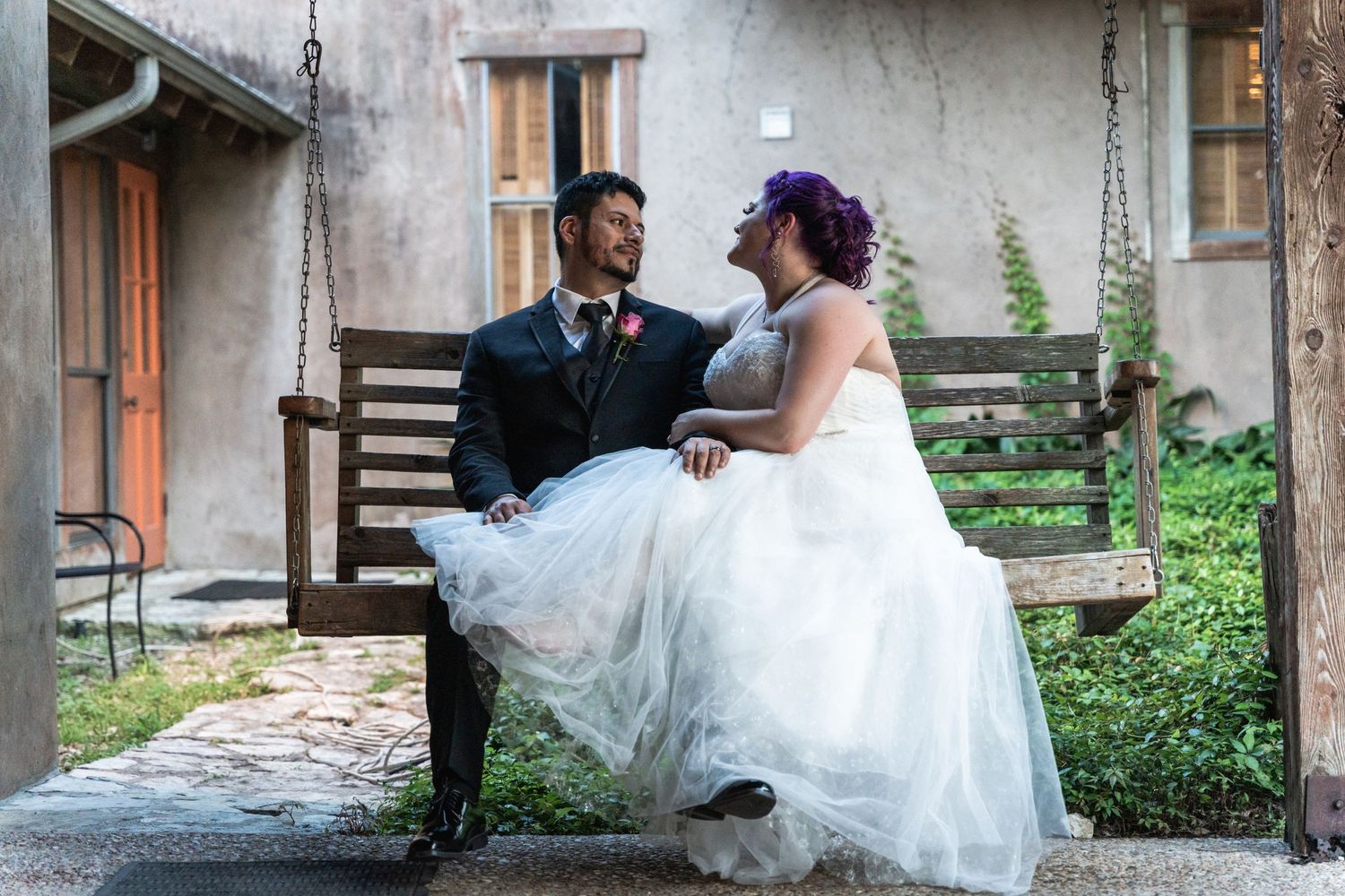 A couple shares a tender moment on a porch swing at their rustic wedding venue.