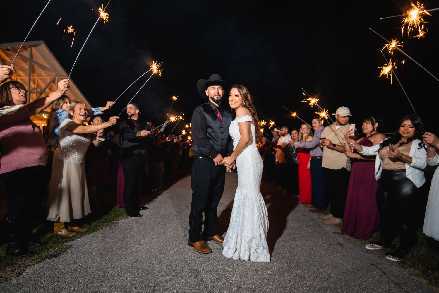 Wedding sparkler exit with guests lining pathway at night.