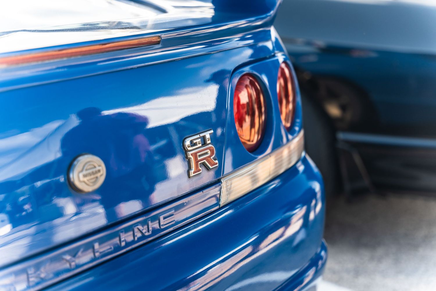 Close-up detail of blue Nissan GTR's iconic round taillights and badge.