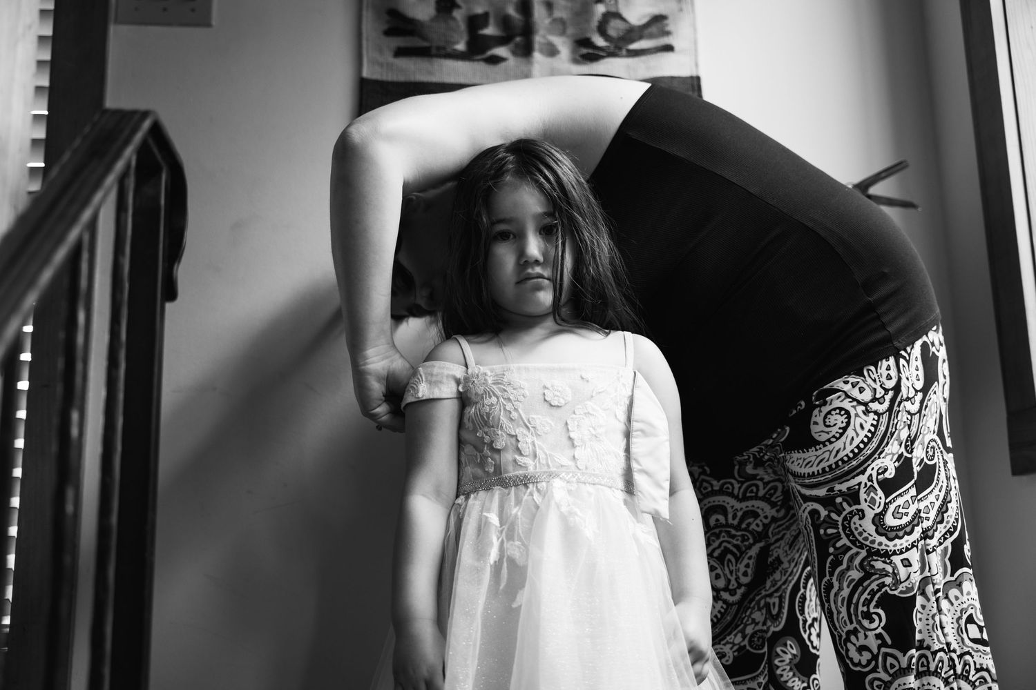 A black and white photo showing someone helping with formal attire preparations.