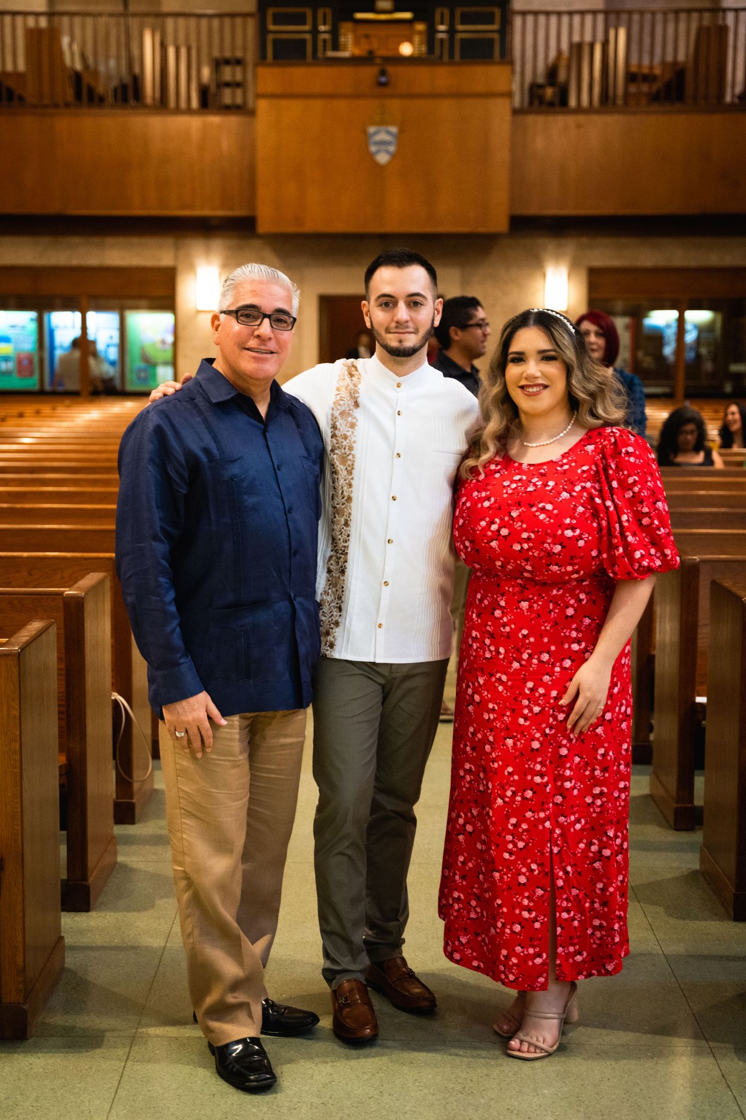 Family group standing together in church pews with wood paneling and warm lighting.