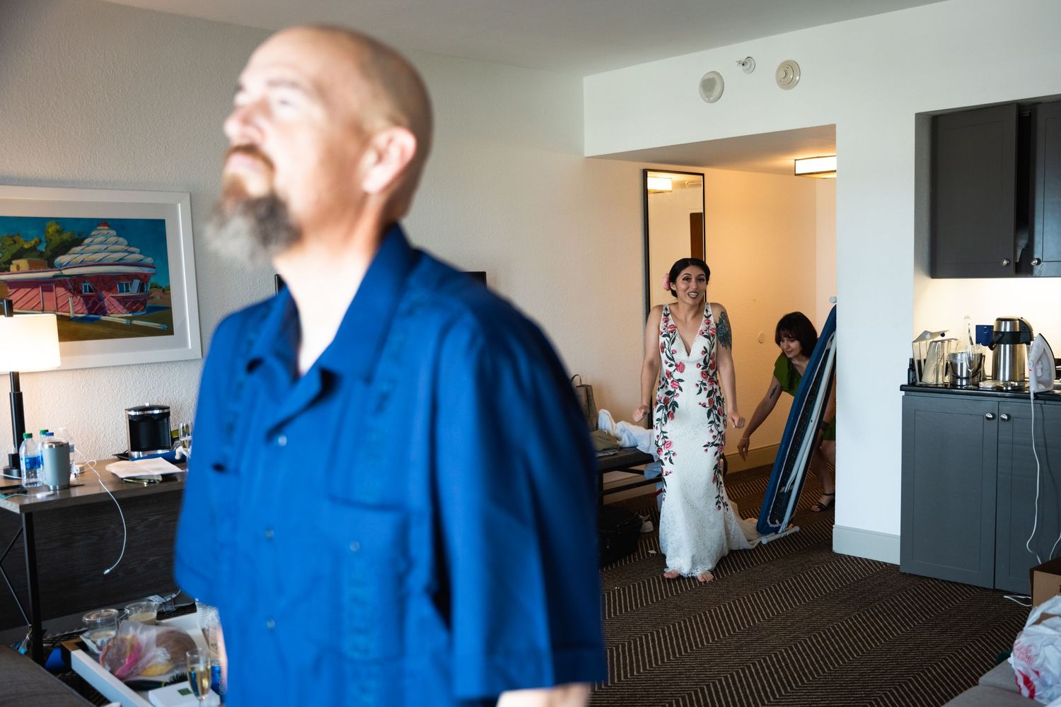 Wedding day scene in hotel room with person in blue shirt and bride visible in background.