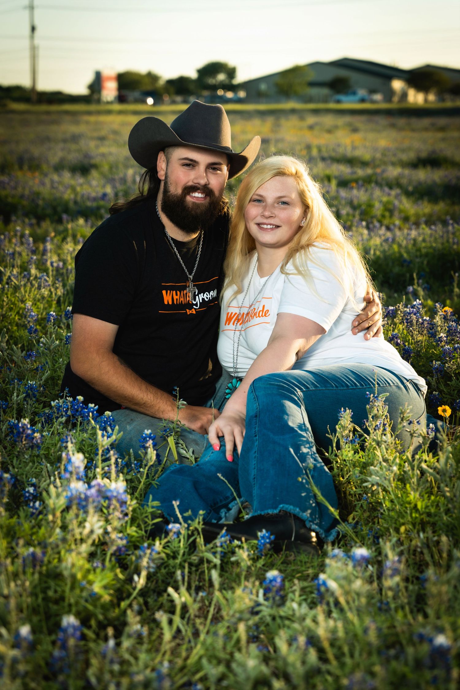 Couple posing in Texas bluebonnet wildflower field at dusk.