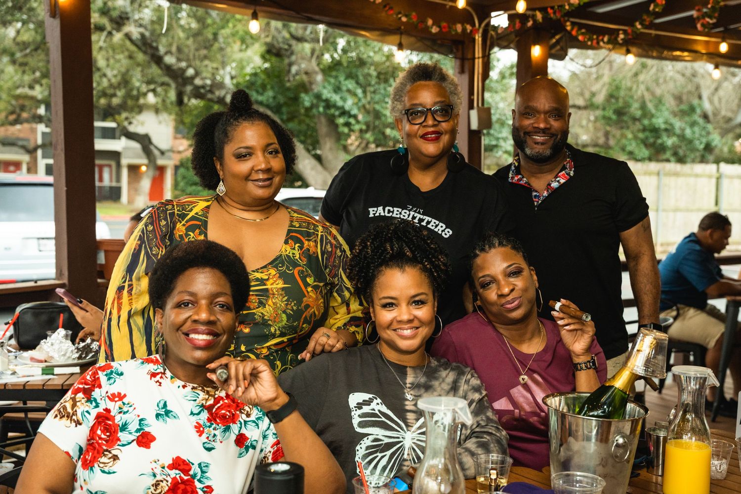 Group of friends enjoying drinks and conversation at an outdoor restaurant patio.