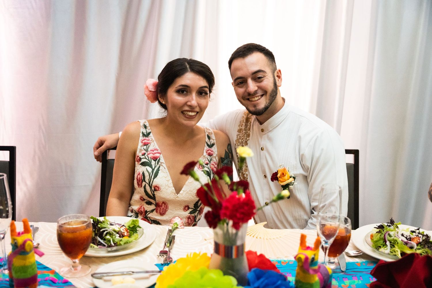Dining couple enjoys a colorful wedding reception meal with bright table decorations.