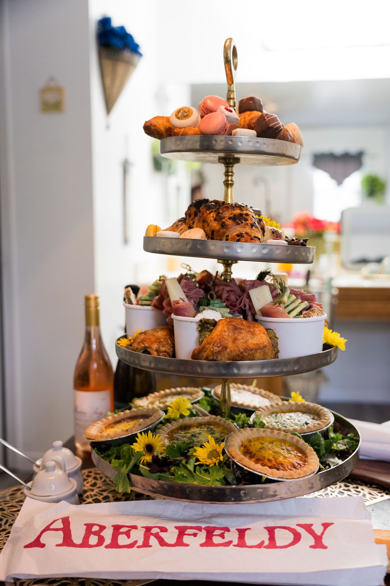 A tiered serving platter displays an assortment of appetizers and desserts with an Aberfeldy sign visible in the foreground.