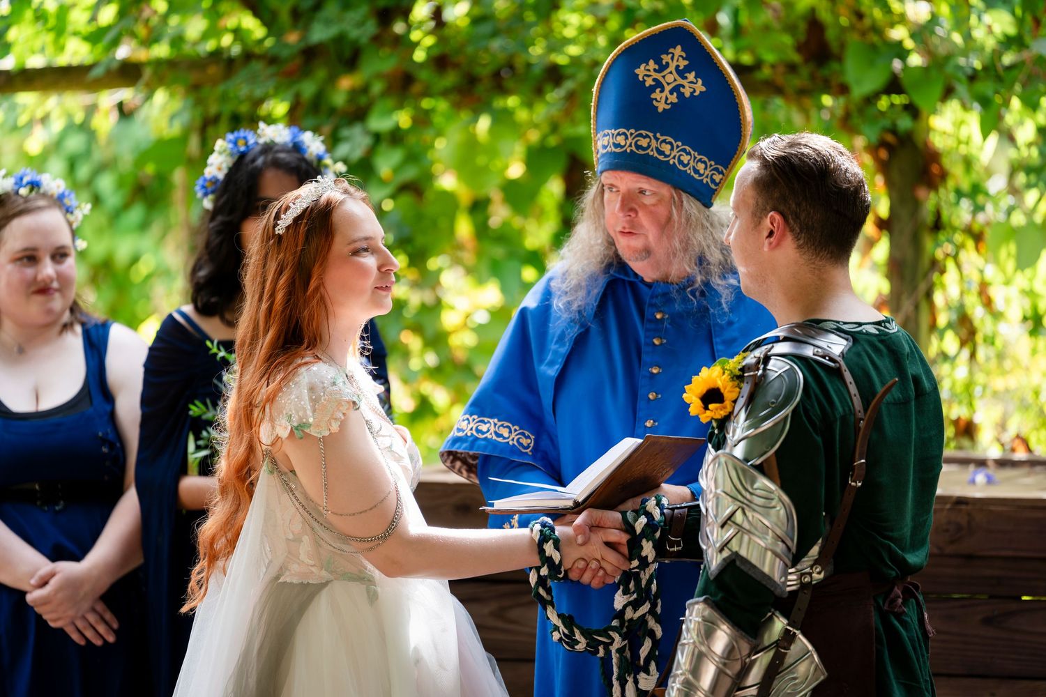 Bride and groom exchange vows during an outdoor wedding ceremony surrounded by lush greenery and guests.