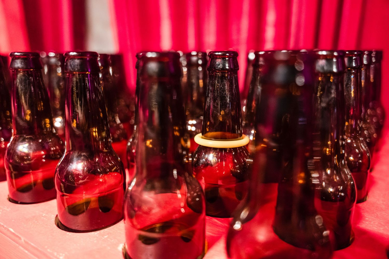 Glass jars filled with liquid illuminated by red lighting create a moody atmospheric display on shelves.