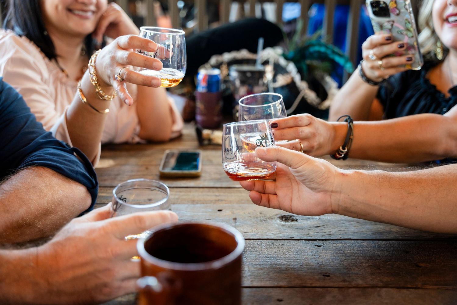 People sharing drinks and socializing at a rustic wooden table with beer glasses and beverages.