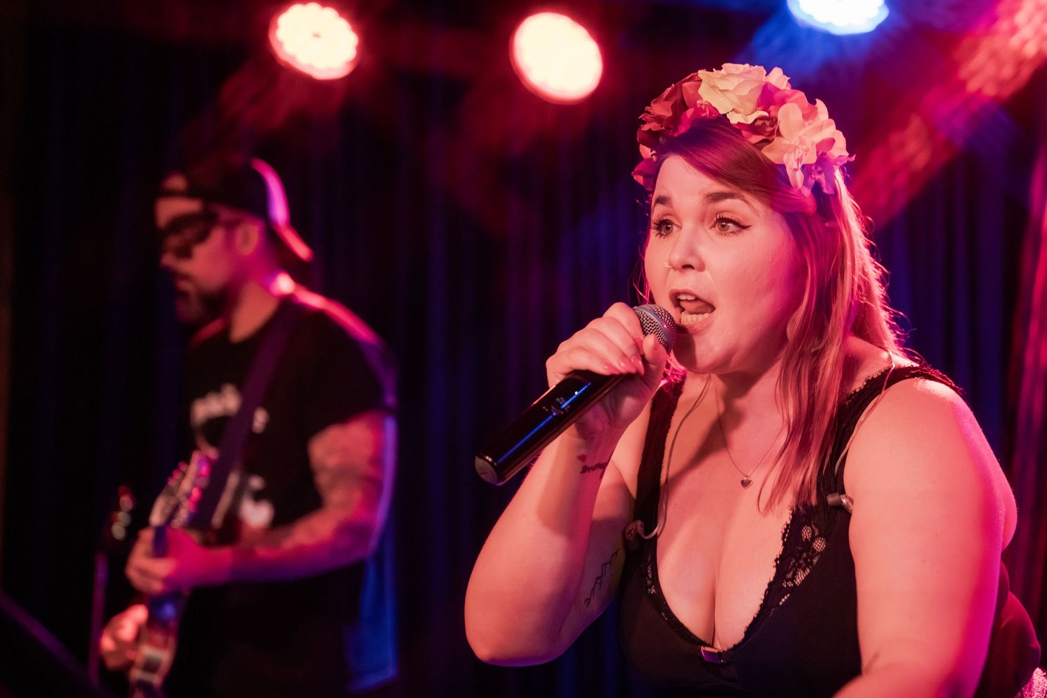 A performer sings on stage under dramatic red and blue lighting during a live music performance.