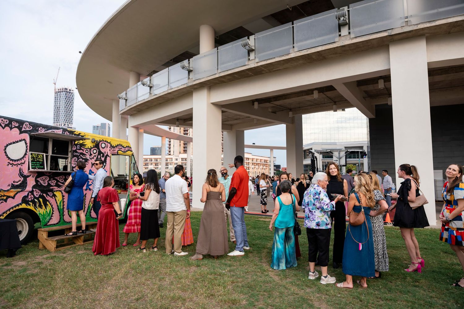 Wedding guests line up outdoors under a covered walkway for a receiving line at a celebration event.