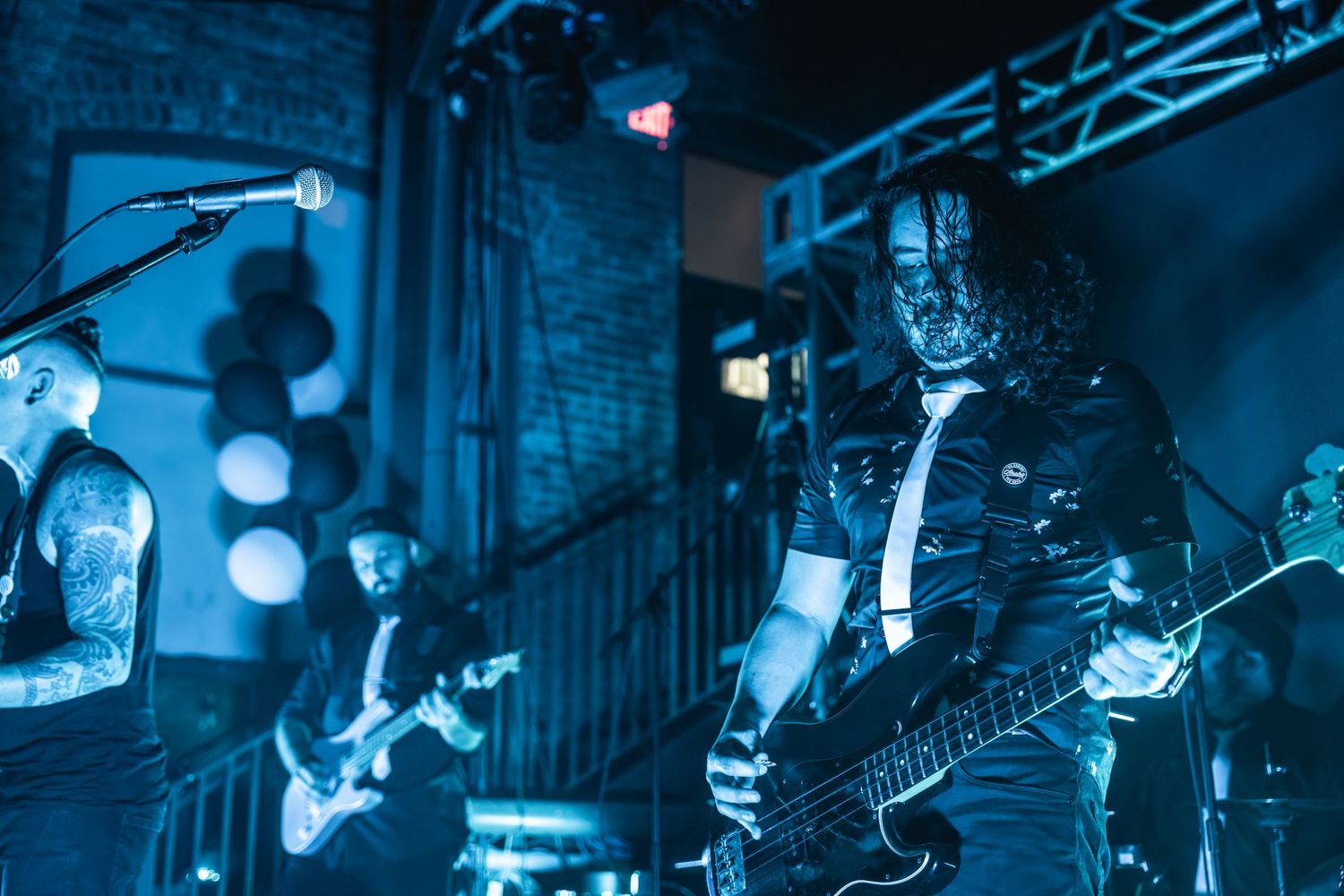 Musicians perform on stage with dramatic blue lighting and stage effects.