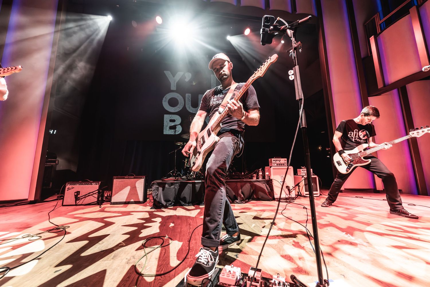 Musicians perform under bright stage lights with dynamic camera angle capturing intense performance.
