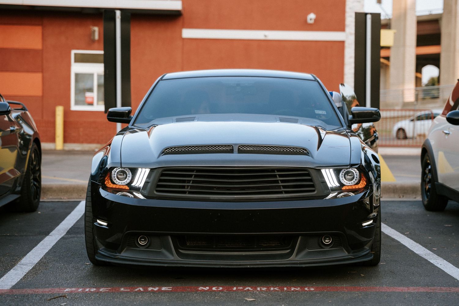 Front view of a menacing black Ford Mustang with custom headlights and hood scoop.