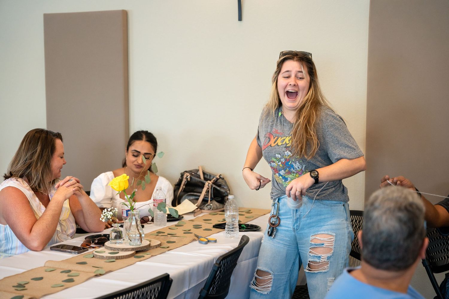 Lively party scene with guests laughing and socializing around decorated dining tables.