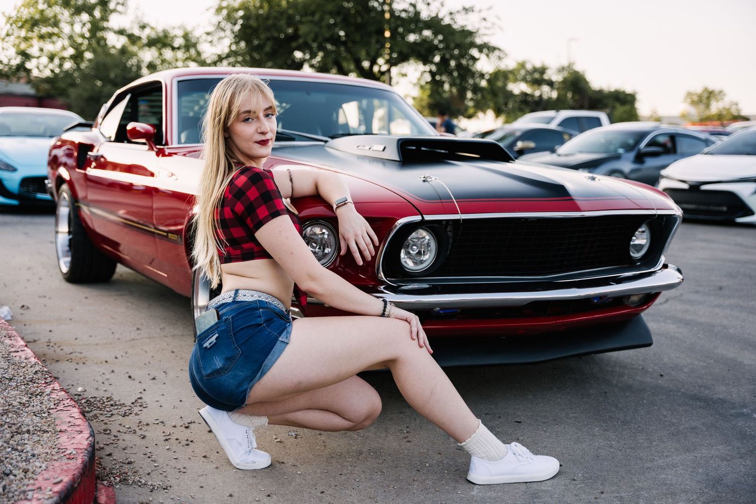 Red vintage Mustang muscle car displayed at outdoor car show.
