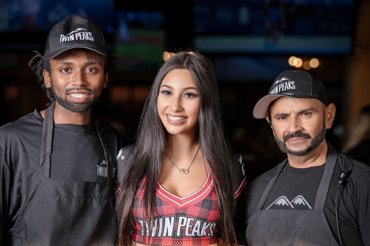 Restaurant staff members pose together wearing Twin Peaks branded uniforms.
