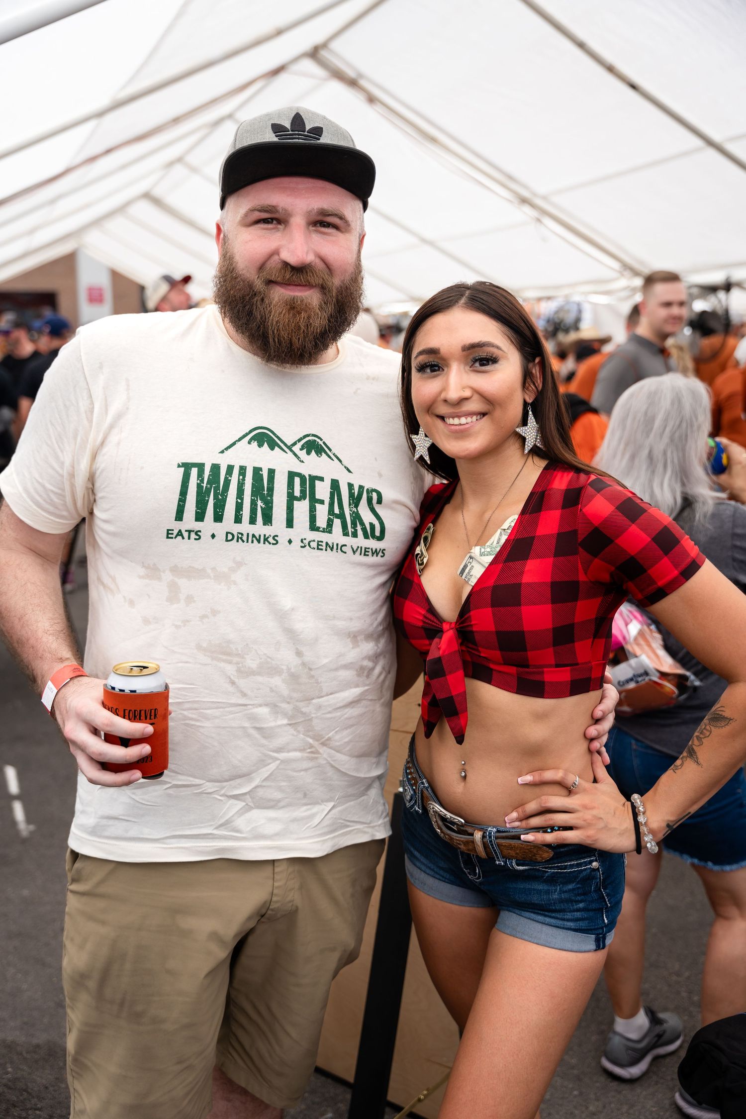 Attendees pose together at festival, one wearing Twin Peaks shirt and other in plaid.