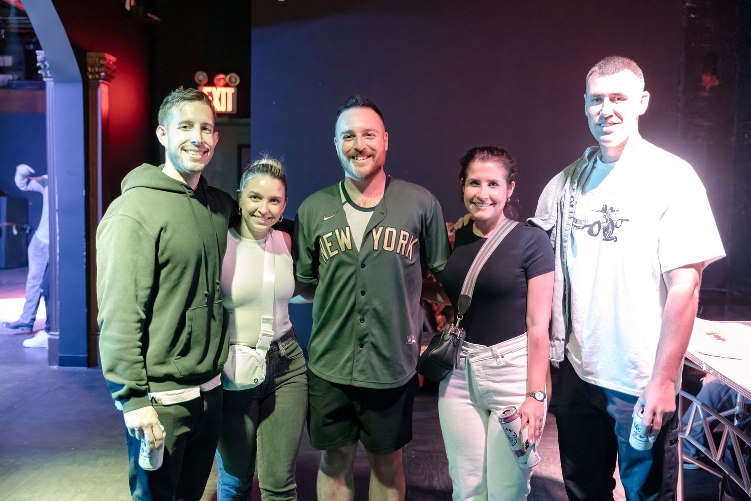 Group of people posing together backstage at a music venue.