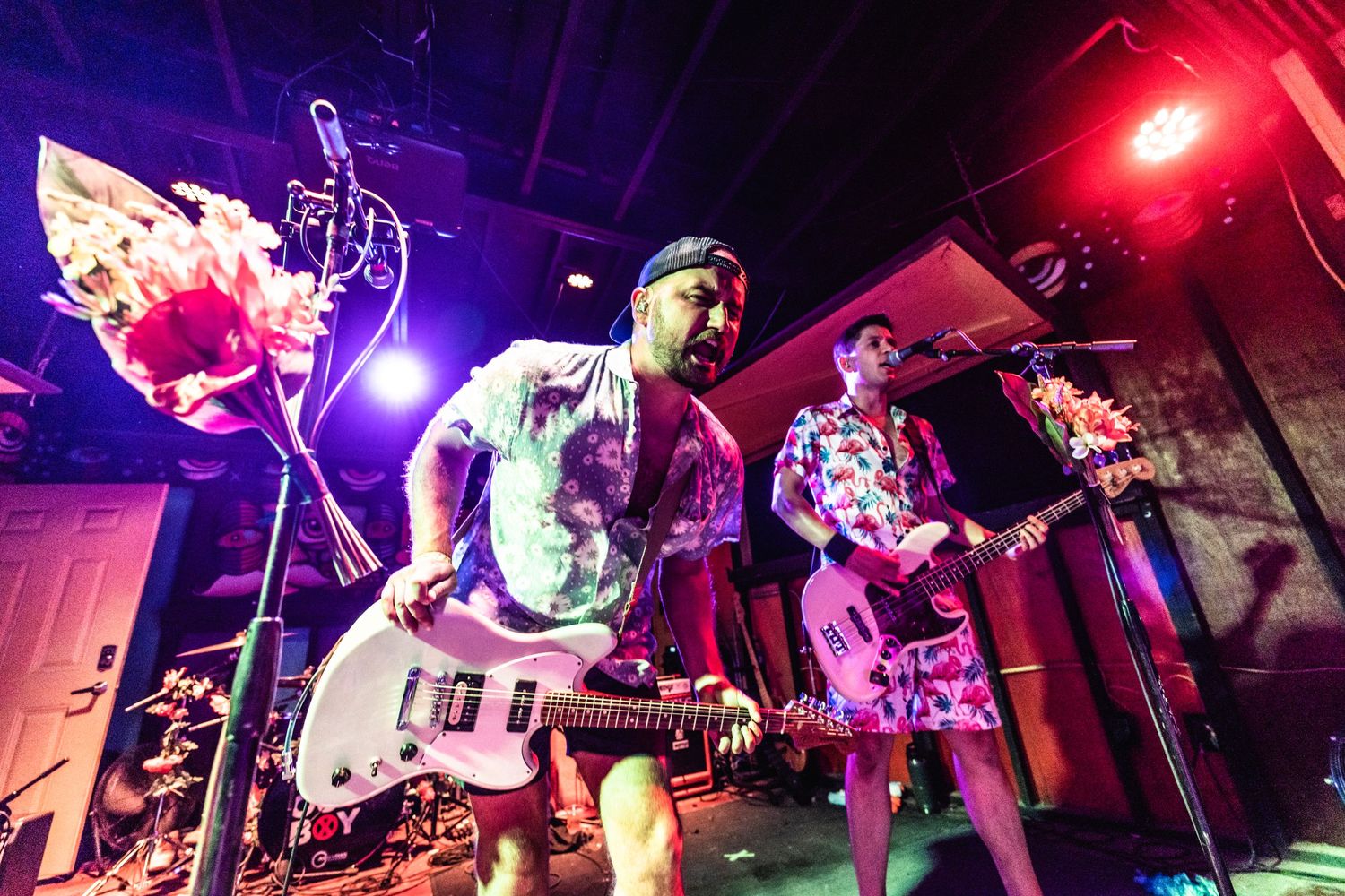 Rock band performing on stage with colorful lighting and electric guitars.