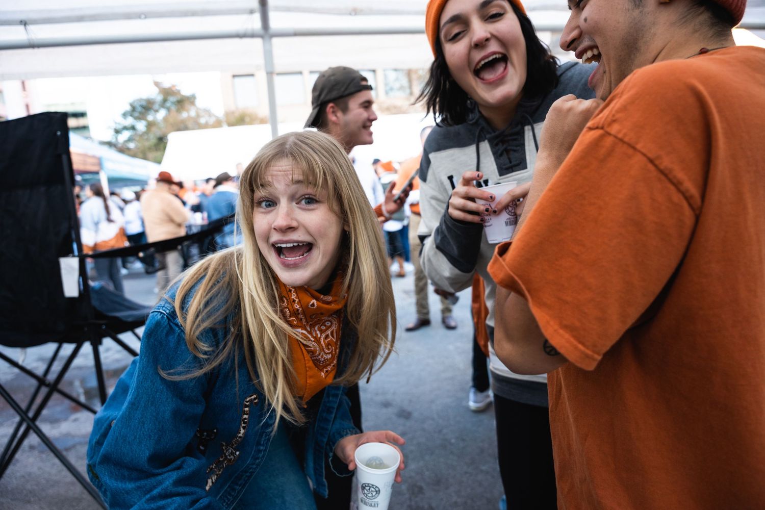 Students celebrating and laughing during a tailgate party with refreshments and outdoor seating.