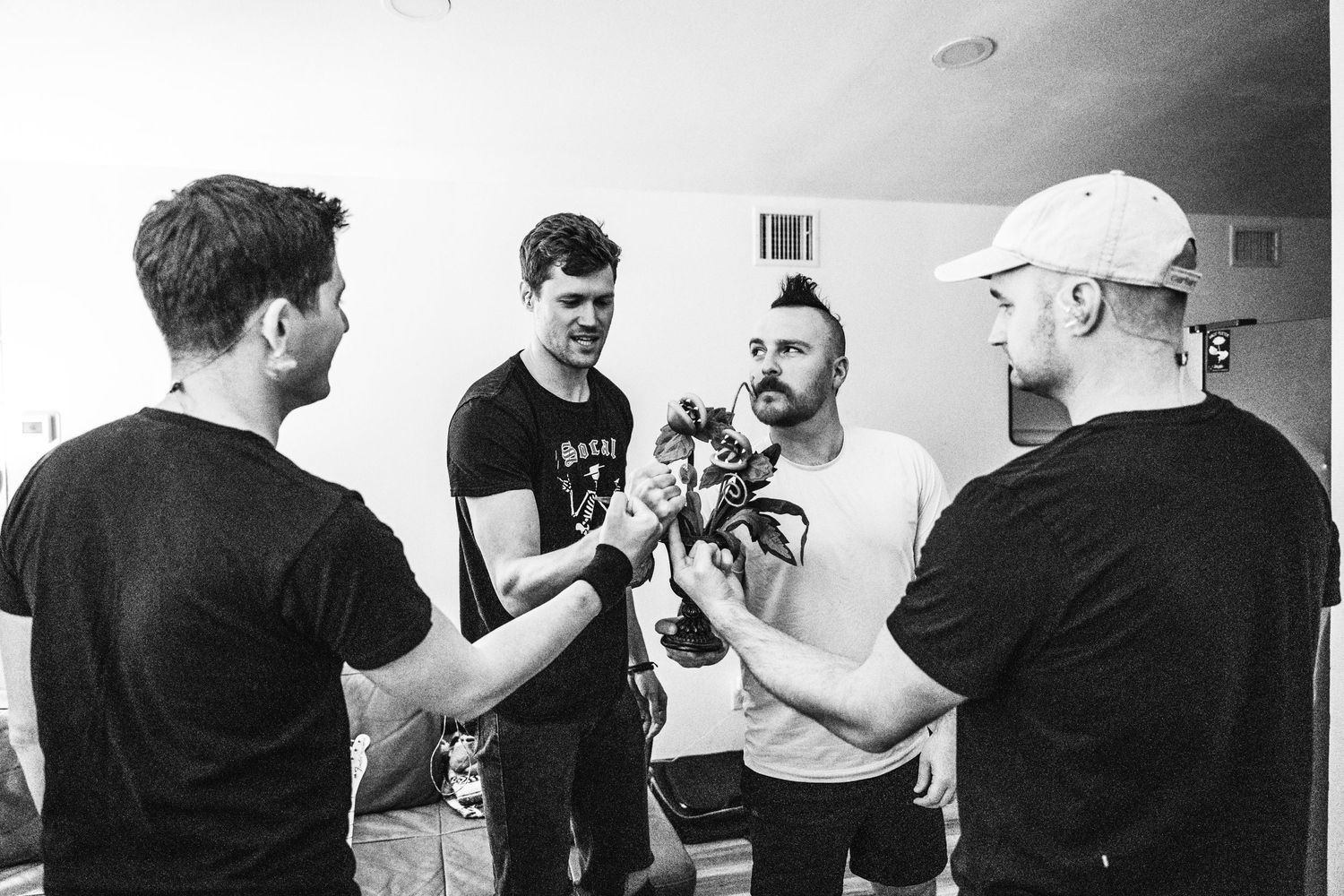 Group of musicians gathered backstage having a pre-show discussion in black and white.