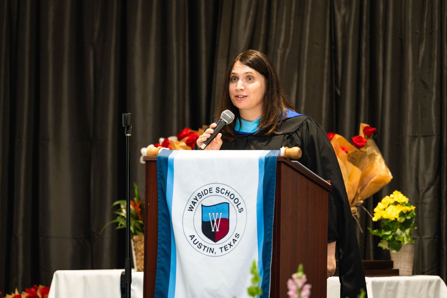 Speaker giving a presentation at a podium with university logo and flowers.