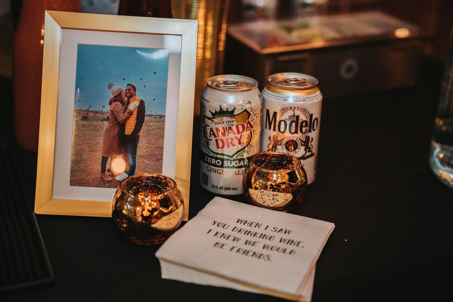 Model Fox beer cans and framed photo displayed on dark surface with candlelight.