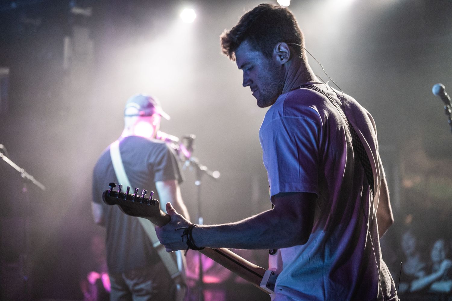 Silhouetted guitarist performs under dramatic stage lighting during concert.