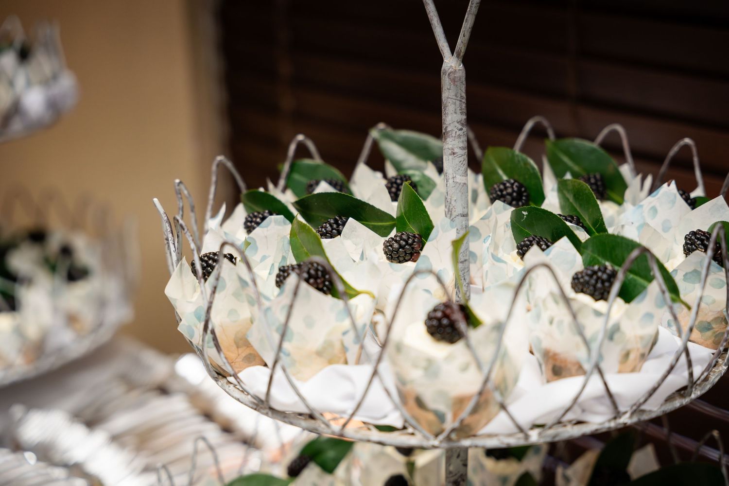 White paper cones filled with appetizers displayed in an elegant wire basket with green garnish.