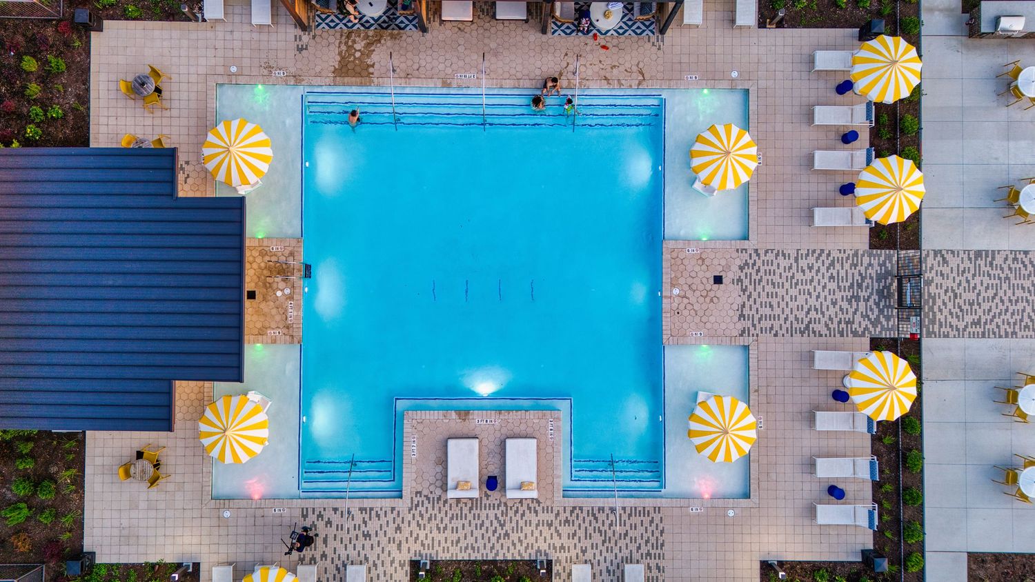 Birds-eye view of rectangular pool with yellow sun-shaped decorations and lounge chairs.