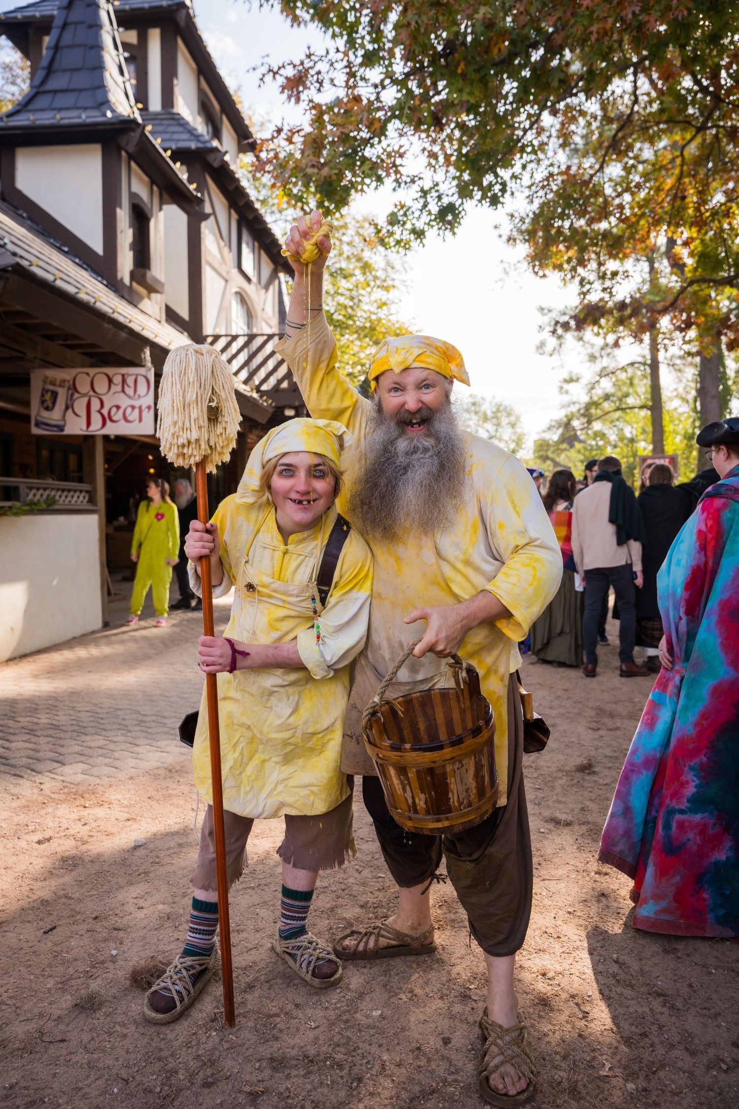 Performers in yellow medieval peasant costumes pose together at renaissance fair.