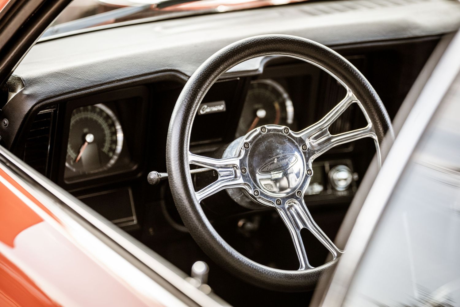 Interior shot of a classic car showing vintage steering wheel and dashboard gauges.
