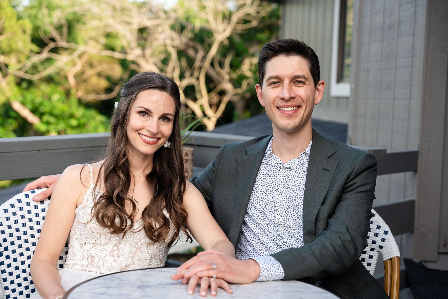 Couple sitting together on outdoor patio furniture at wedding reception.