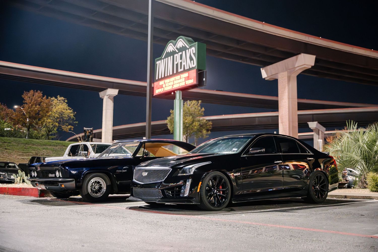 Vintage and modern vehicles parked in front of Jim's restaurant at night.