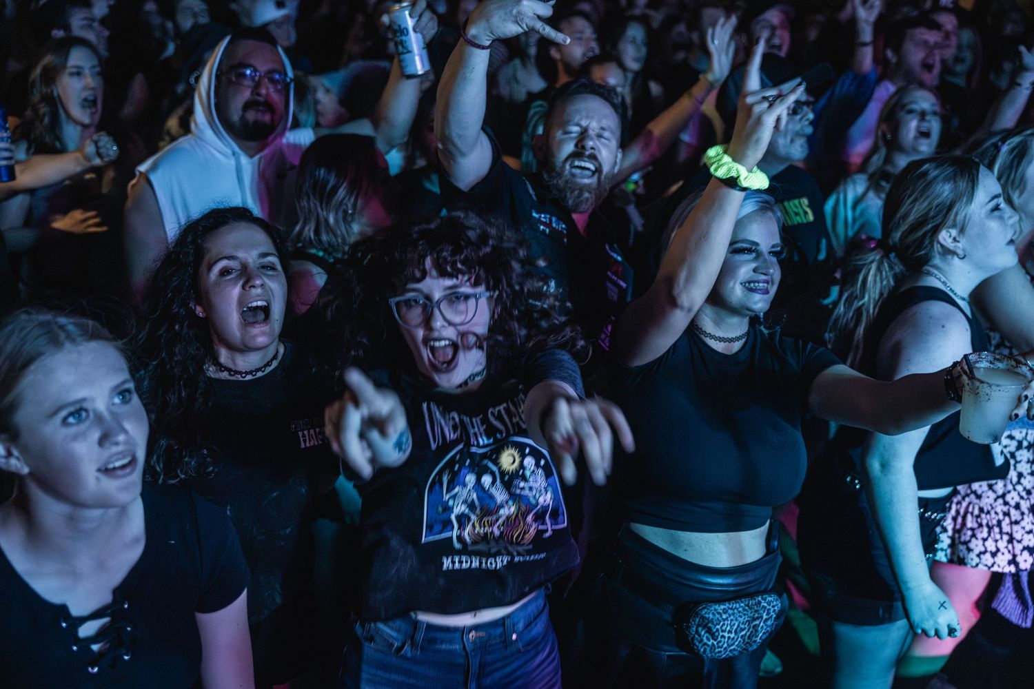 Concert attendees cheer and raise their hands during an intense musical performance.