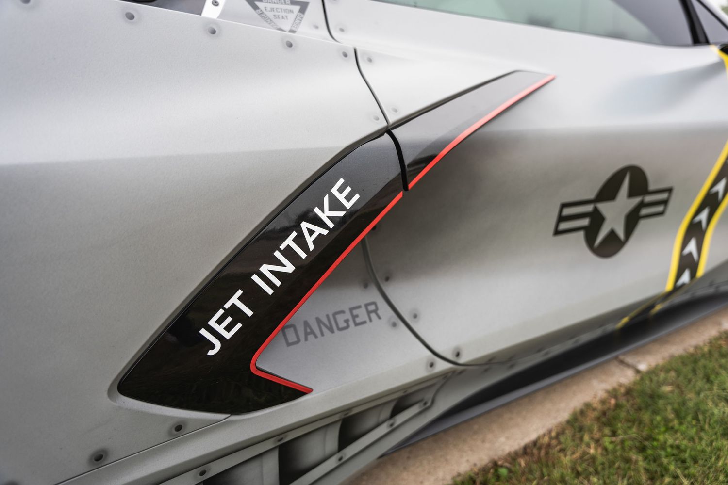 Close-up detail of a Jet Intake warning label on a silver aircraft-inspired vehicle.