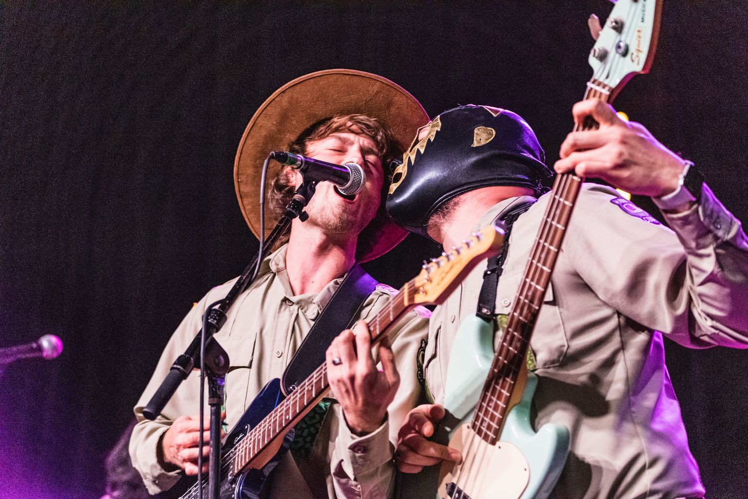 Close-up of two performers playing guitars together during concert performance.