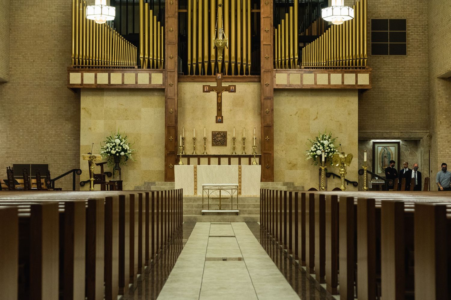 Interior of a traditional church sanctuary with wooden pews and pipe organ centered around a cross on the altar.
