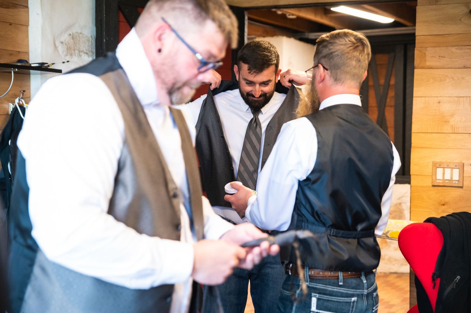 Men in formal attire getting dressed in wooden cabin.