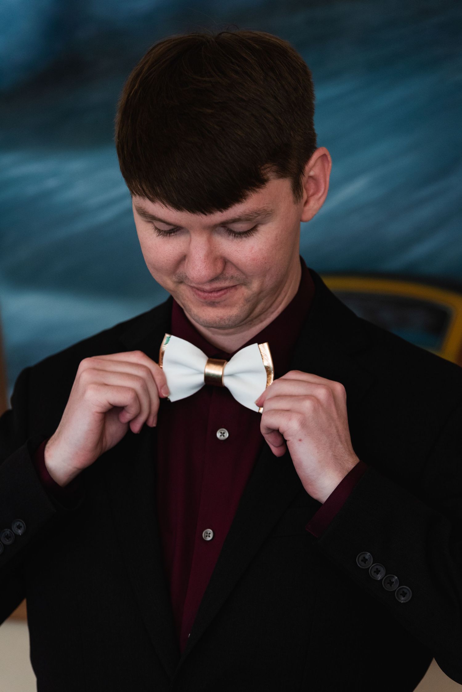 Close-up shot of someone adjusting a white bow tie against a dark suit.