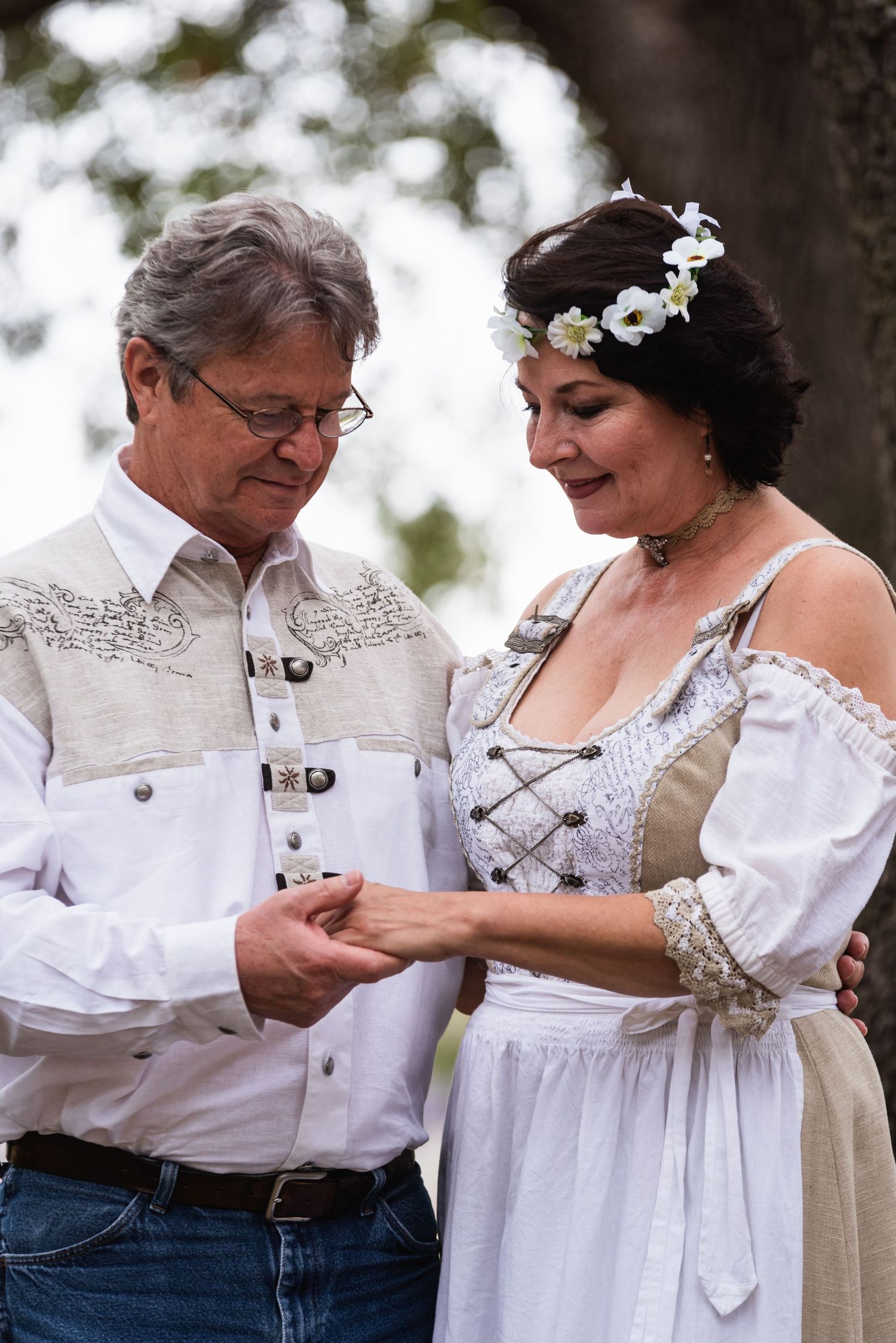 A couple in vintage-inspired clothing shares a tender moment while exchanging rings.