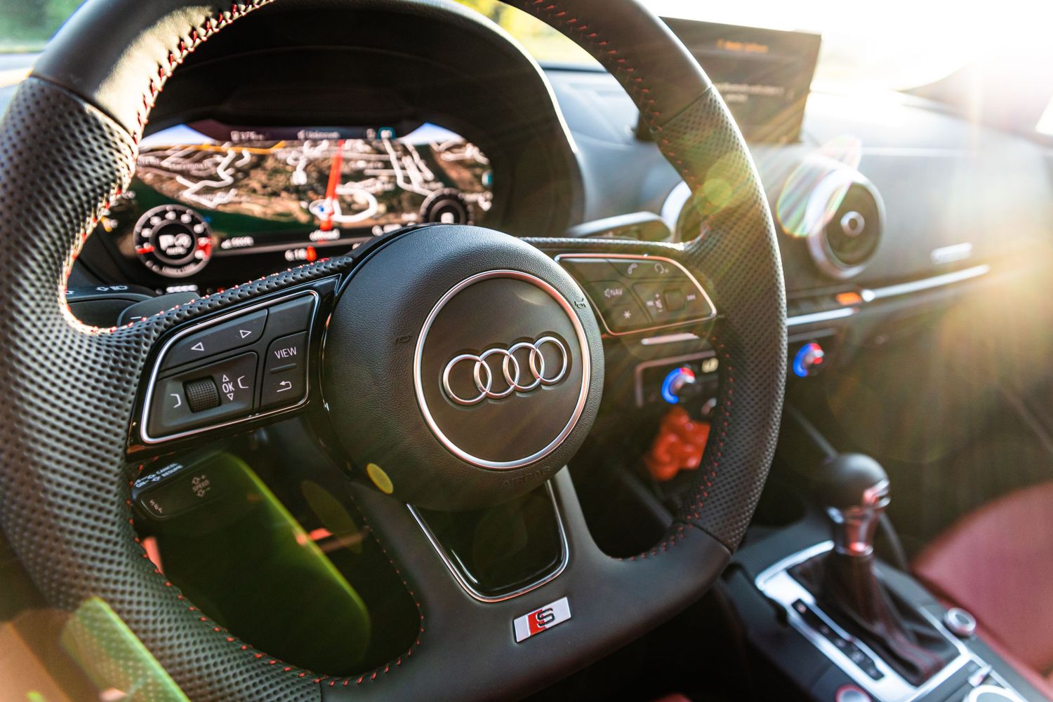 Audi steering wheel with sunlight streaming through showing detailed controls.